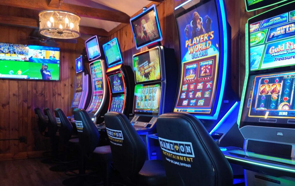A row of slot machines with a sports TV broadcast on the TV in the background